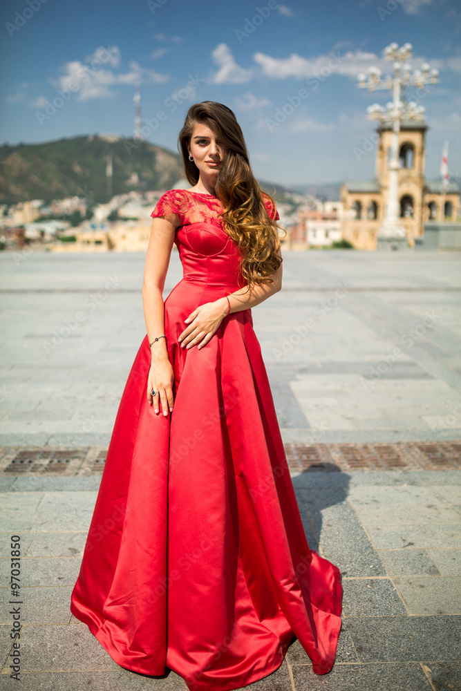 Beautiful brunette young woman wearing dress and walking on the street Beautiful brunette young woman wearing dress and walking on the street