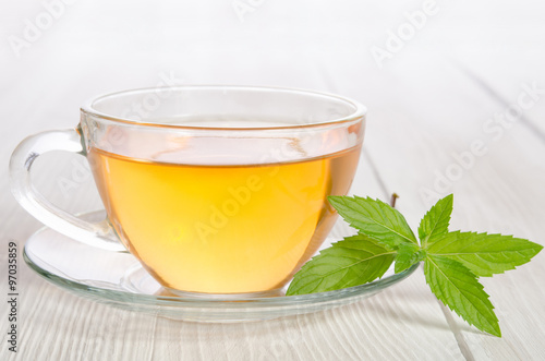 Glass cup of tea with mint on the white wooden table