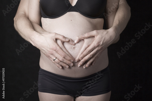 Pregnant Belly with fingers heart symbol. 