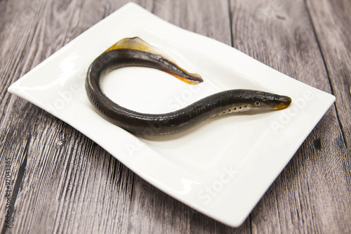 Foto Fresh live fish lamprey on porcelain plate with lemon.