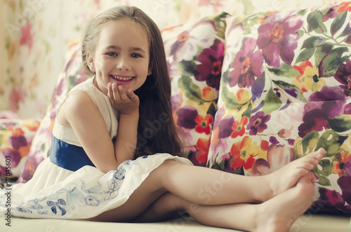 Portrait of cute girl sitting barefoot in the bed