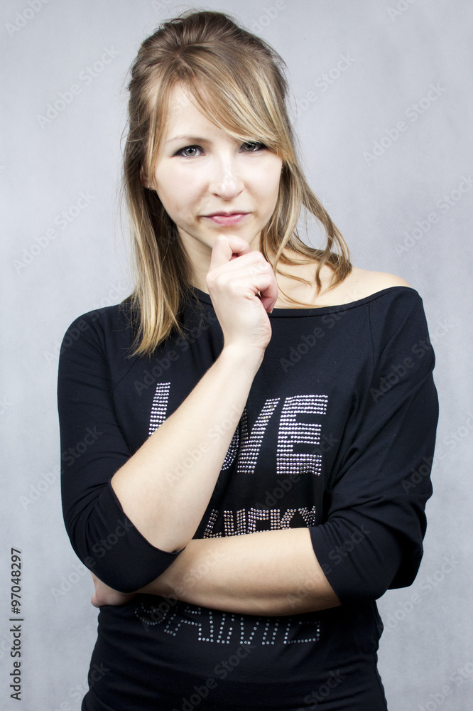 Fototapeta premium Młoda kobieta, blondynka. Ubrana na czarno podpierająca ręką głowę.