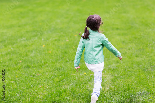 little girl walking along summer green meadow
