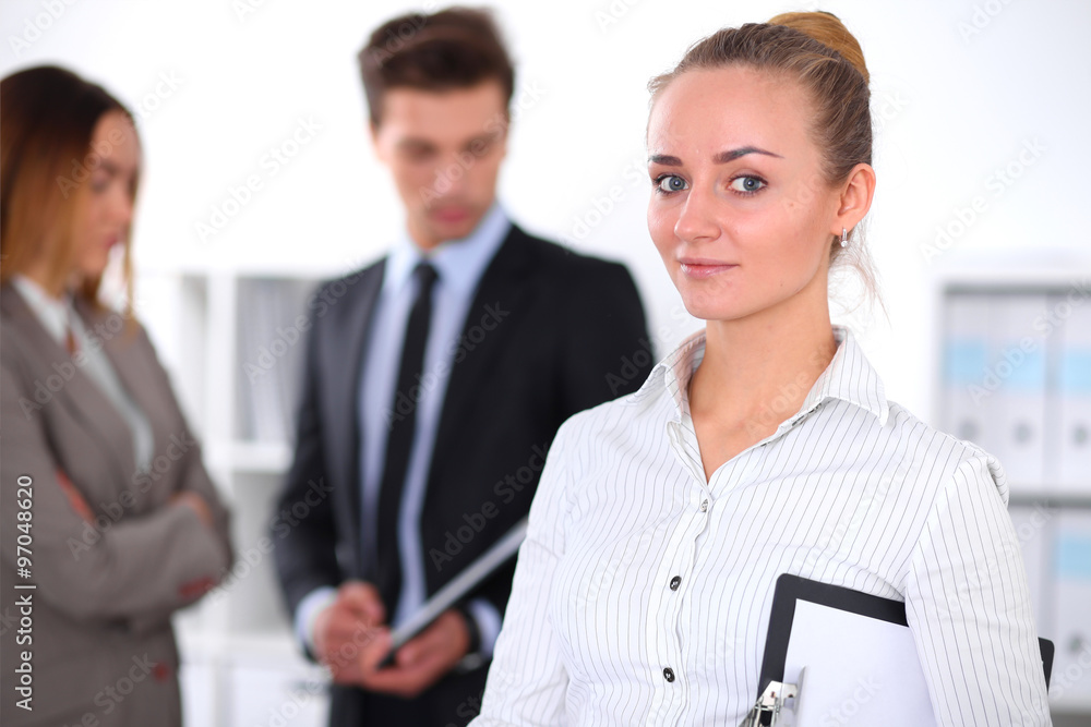 Pretty businesswoman in office with colleagues in the background Pretty businesswoman in office with colleagues in the background