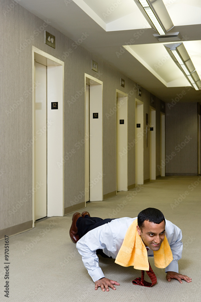 Office worker doing push ups in corridor