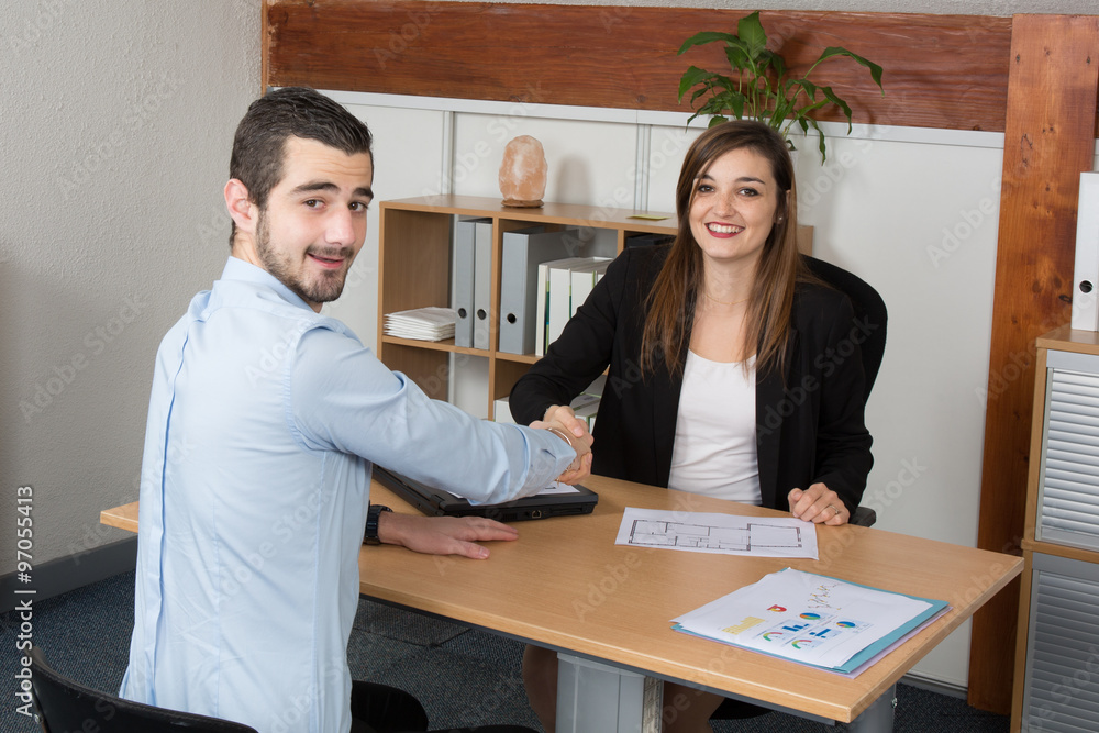 Business woman looking at camera while shaking hand at office desk Business woman looking at camera while shaking hand at office desk