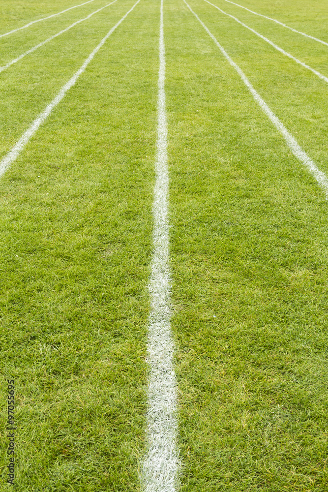 Running track lines marked on the grass on a sports field.