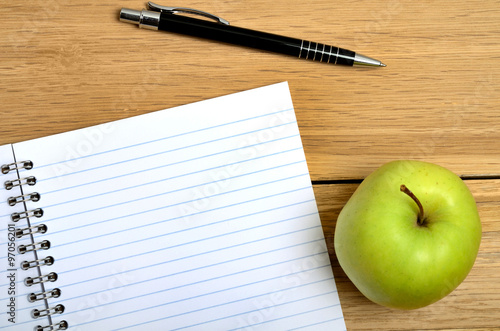 Notebook with apple fruit and pen