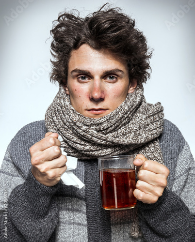 Fényképezés Man Cold / Ill young man with red nose, scarf, sneezing into handkerchief