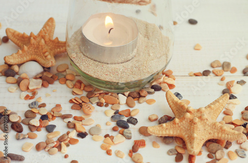 Tea light candle in jar with sea sand. Framed pebbles, starfish.Summer beach style home decor.