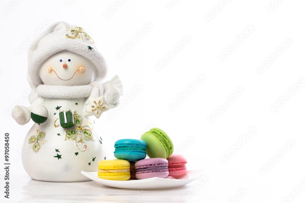 collection of brightly colored French macarons on white background, standing next to a snowman