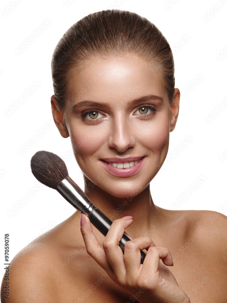 Portrait of a young healthy and beautiful girl with nude make up and makeup brush in her hand