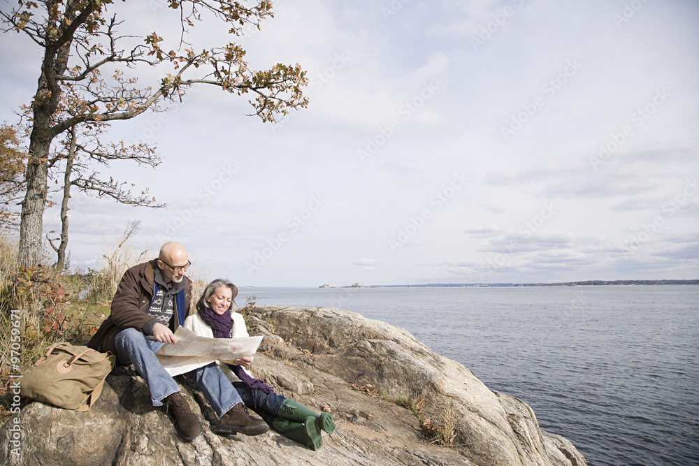 Mature couple reading a map near lake Mature couple reading a map near lake