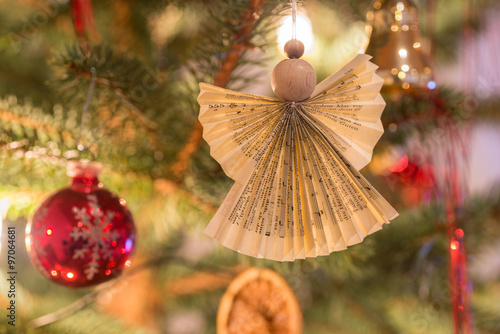 Selbst gebastelter Weihnachtsengel aus Holz und Papier an dekoriertem Tannengrün