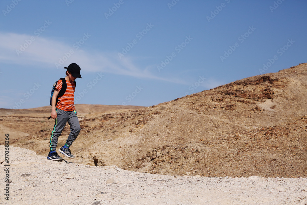 Cute 8 years old boy hiking in the desert
