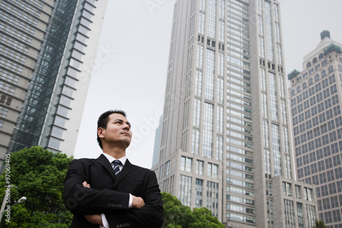 Serious looking businessman near skyscrapers