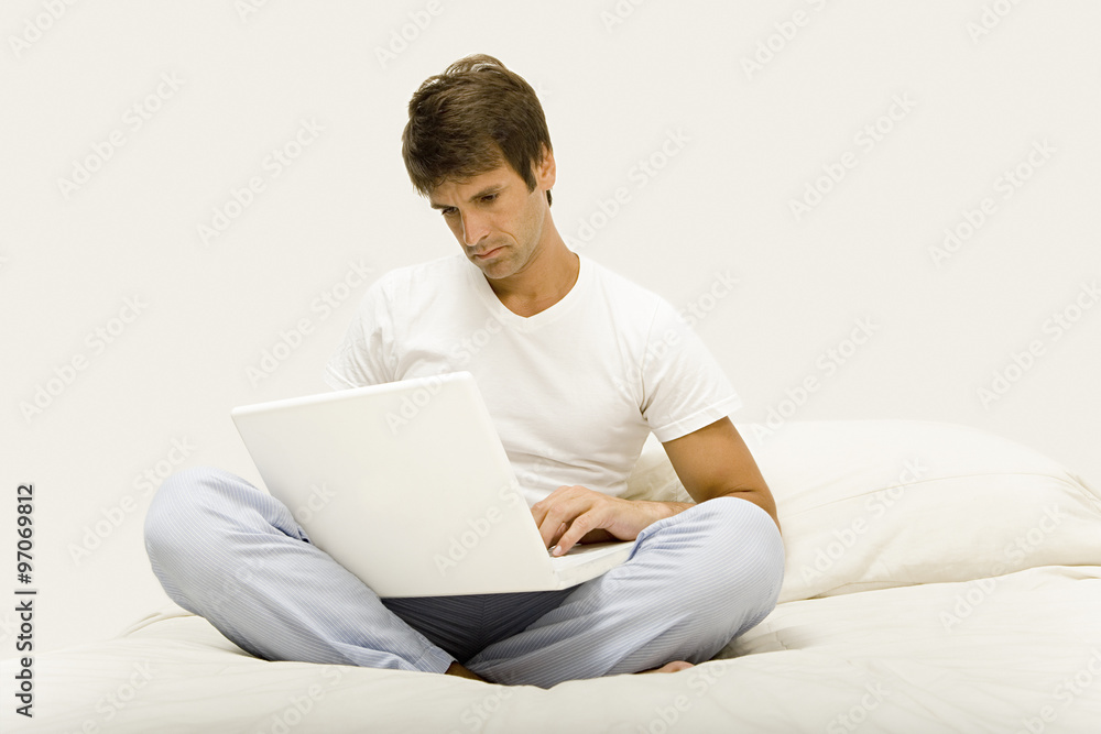 Man sitting on bed using laptop Man sitting on bed using laptop