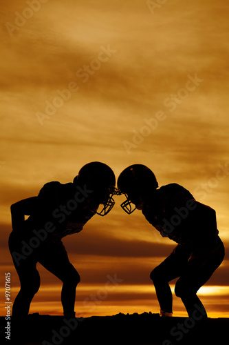 silhouette of two football players in the sunset stand