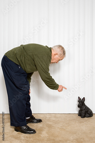Elderly man pointing at dog ornament © xixinxing