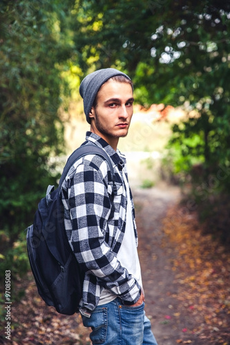 Portrait of young handsome man with backpack wanderer walk in th