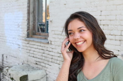 Beautiful teenager calling by phone outside with copy space on the left side 