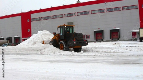 tractor cleans snow on the territory of the warehouses