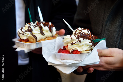 Tourist holding Brussels gaufre with cream. Vintage effect applied with intentional noise.