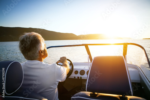 Fototapeta mature man driving speedboat