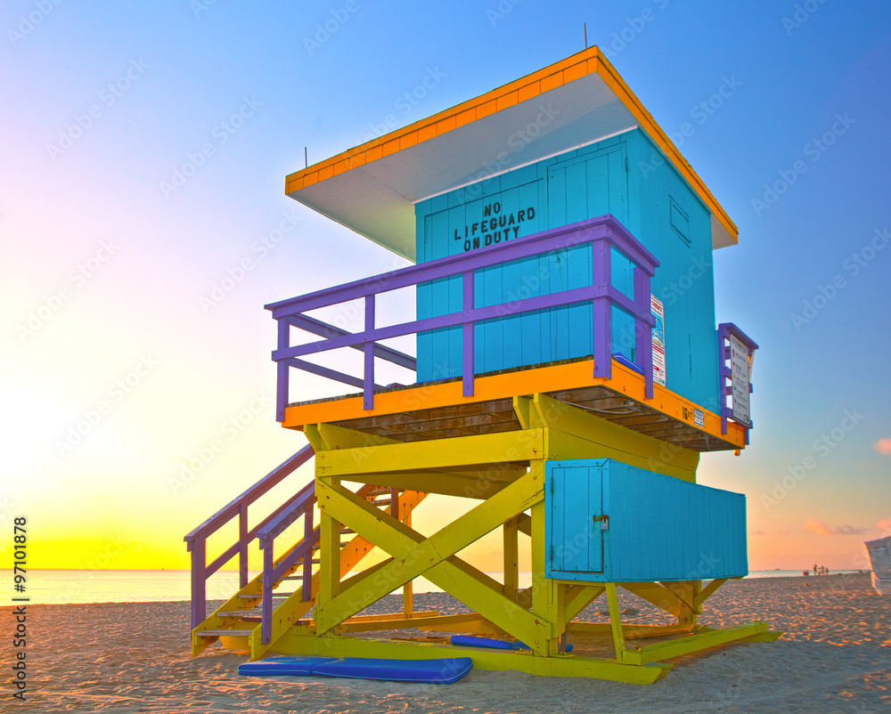 Sunrise in Miami Beach Florida, with a colorful lifeguard house in a typical Art Deco architecture, at sunrise with ocean and sky in the background.