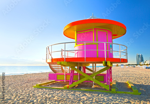 Sunrise in Miami Beach Florida, with a colorful pink lifeguard house in a typical Art Deco architecture, at sunrise with ocean and sky in the background.