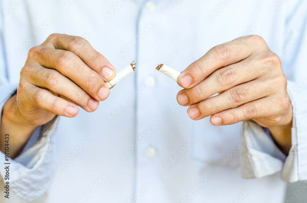 Male hand breaking the last cigarette to stop smoking