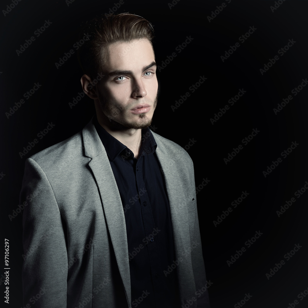 Fototapeta premium Portrait of attractive mysterious young man over black backgroun