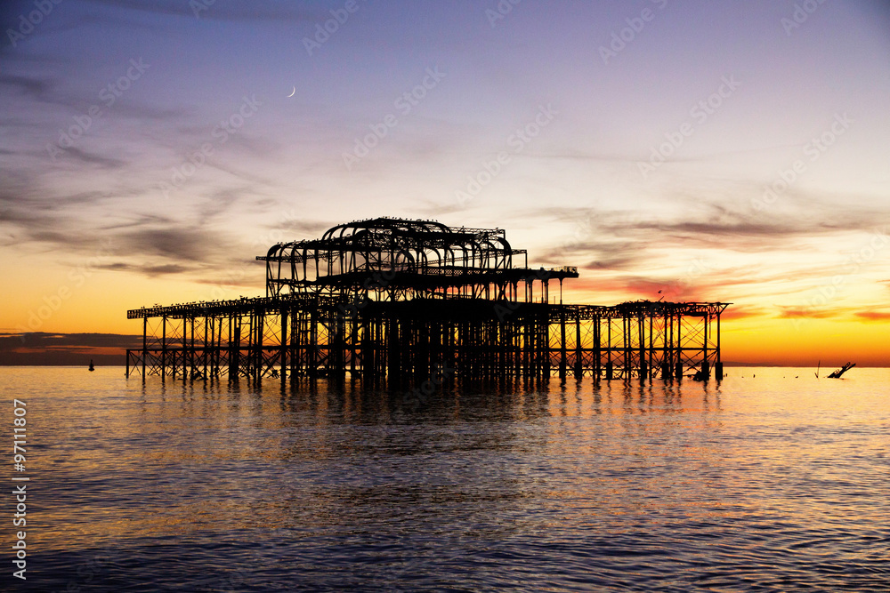 Remains of Brighton Pier left standing in sea at sunset,