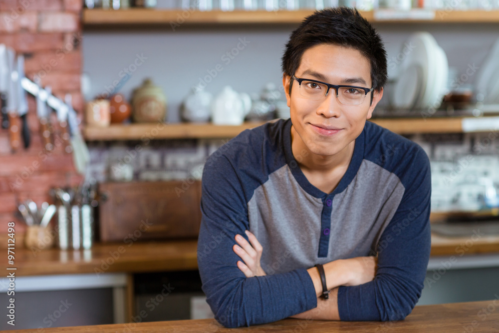 Obraz premium Confident handsome man standing in cafe with arms crossed