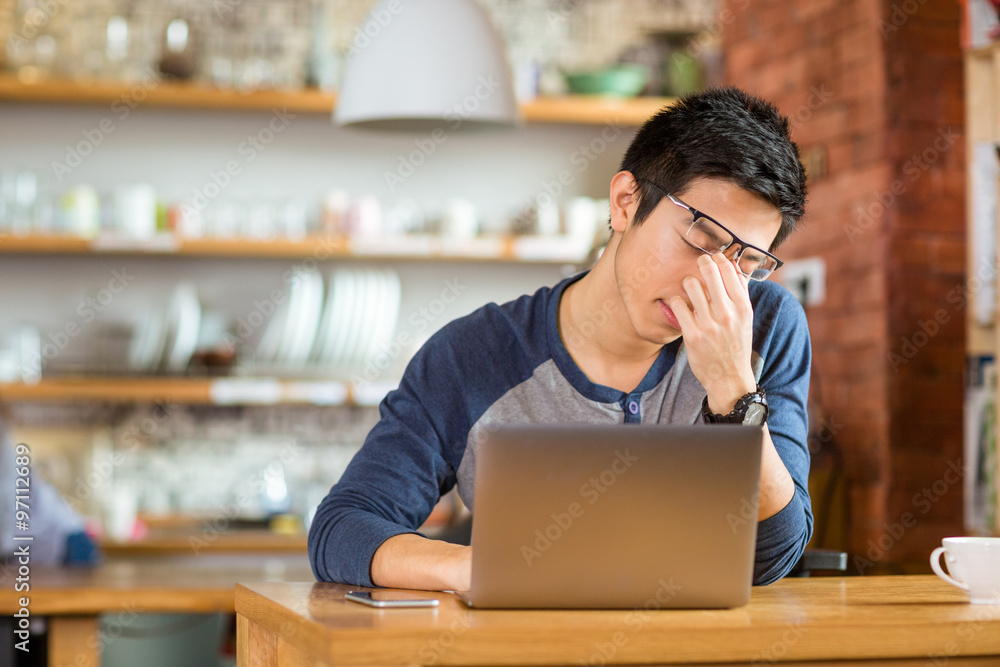Tired exhausted asian male working with laptop Tired exhausted asian male working with laptop