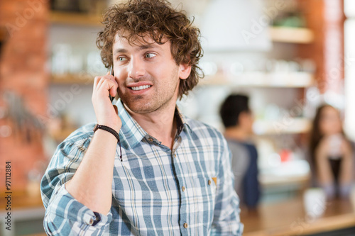 Attractive happy modern young curly man talking on cell phone