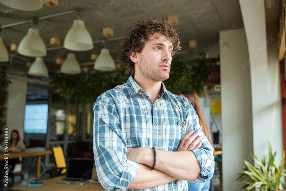 Thoughtful man standing in office with folded hands Thoughtful man standing in office with folded hands