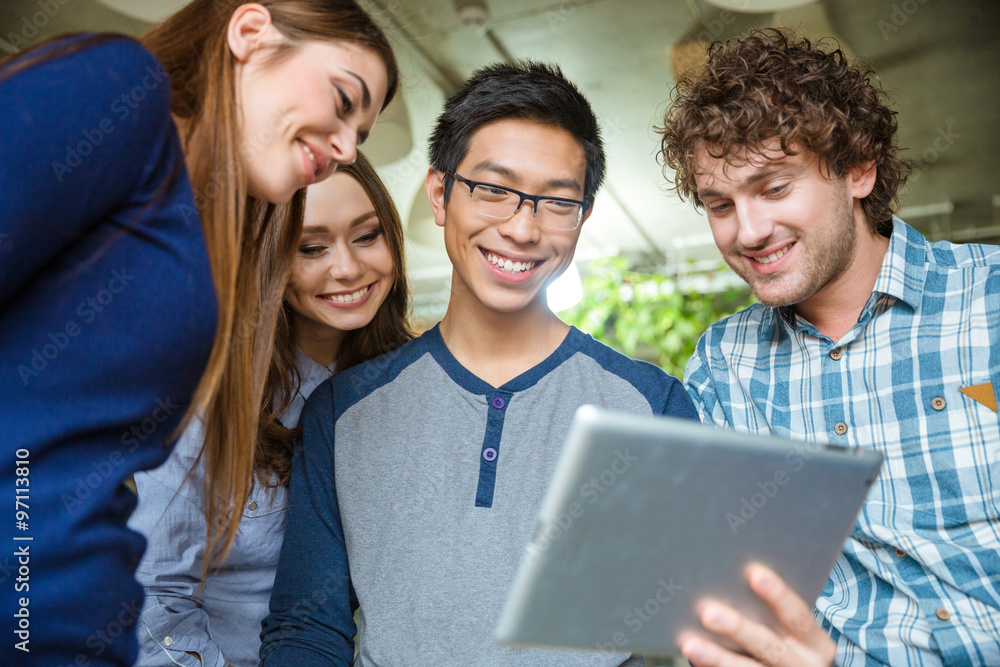 Joyful smiling young friends using tablet Joyful smiling young friends using tablet