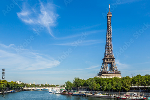 Eiffel Tower  Paris  France  September 11  2015. Shown against a blue sky  with wispy clouds. In the foreground are boats on the river Seine.