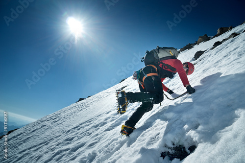 Bergsteiger klettert die Nordwand des Fuscherkarkopf, Österreich. Kletterer schlägt mit den Steigeisen Stufen ins Eis.