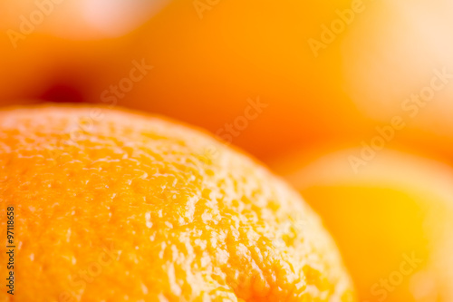 Close up photo of the surface of an orange, with more blurred oranges in the background