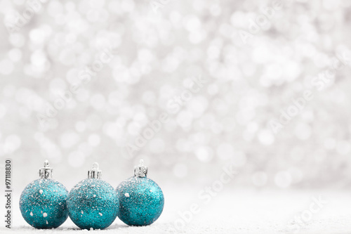 Christmas ball in the snow on blurred light background. A holiday card. Traditional Christmas decorations.