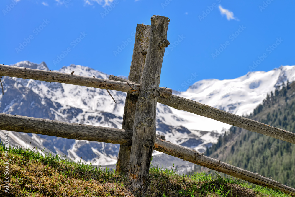 Holzzaun mit Holznägeln in Sulten Südtirol mit Bergen und blauer Himmel im Hintergrund 