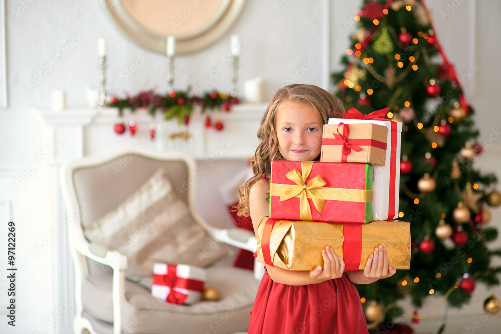 Smiling girl standing with gifts under the Christmas tree. Smiling girl standing with gifts under the Christmas tree.