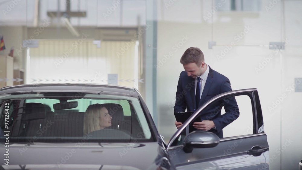 Cheerful manager helping girl with choosing car Cheerful manager helping girl with choosing car