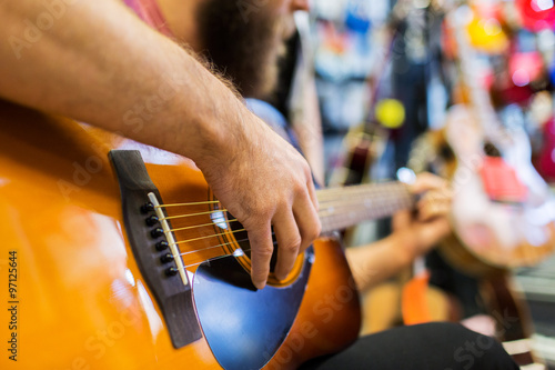 close up of man playing guitar at music store