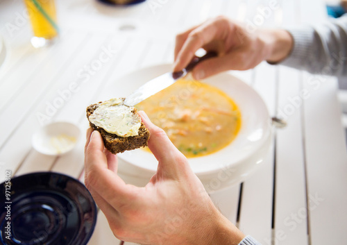 close up of hands applying butter to bread