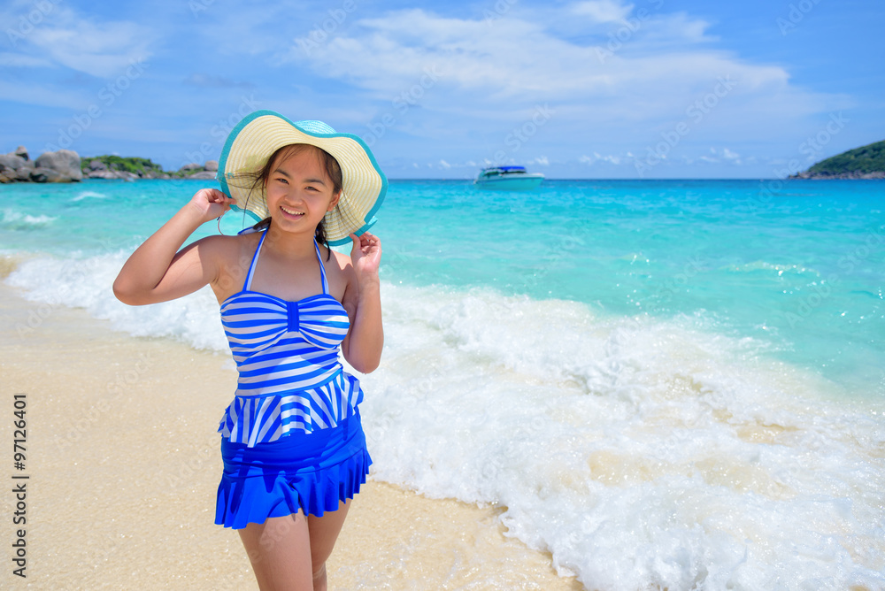 Beautiful woman in a blue striped swimsuit and hat standing poses on beach of sea under a summer sky at Koh Miang Island in Mu Ko Similan National Park, Phang Nga Province, Thailand Beautiful woman in a blue striped swimsuit and hat standing poses on beach of sea under a summer sky at Koh Miang Island in Mu Ko Similan National Park, Phang Nga Province, Thailand