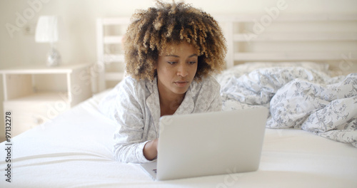 Woman Looking At Laptop In Bed At Home