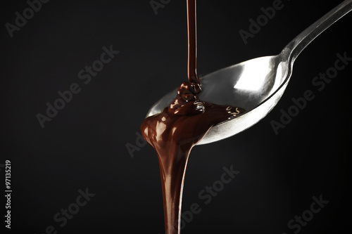 Chocolate poured on a spoon on dark background